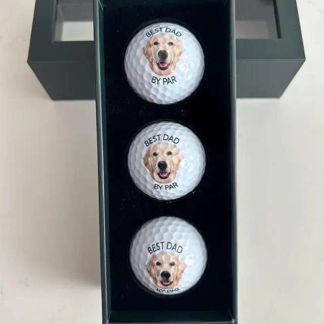 Three golf balls printed with a golden retriever, in the gift box